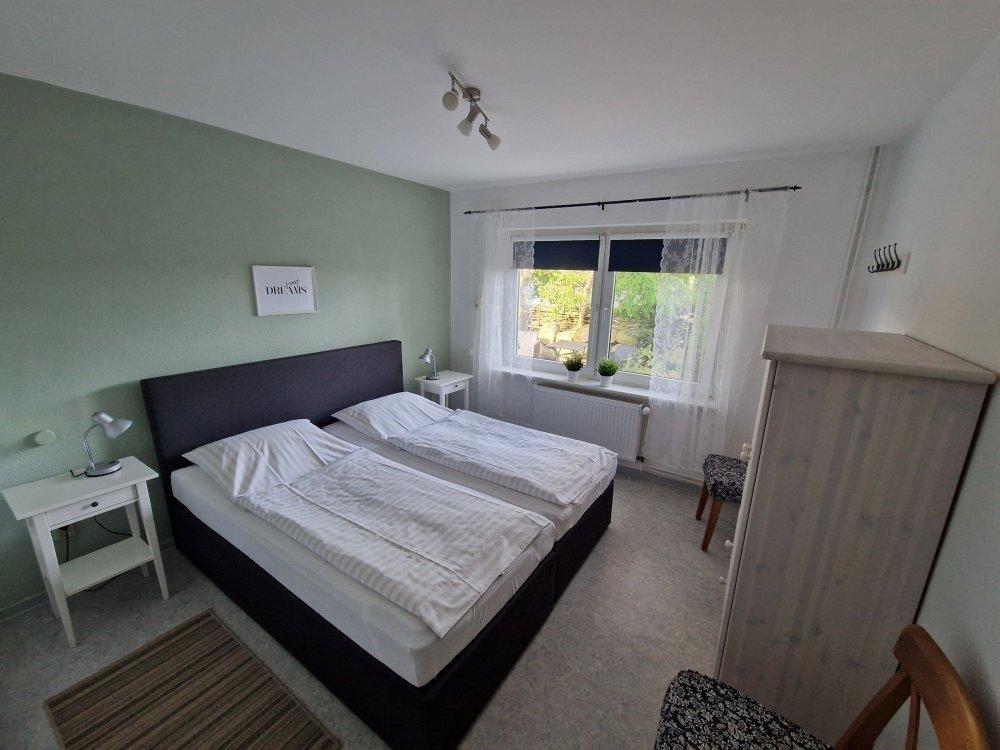 Schlafzimmer mit Doppelbett, Fenster und Schrank.