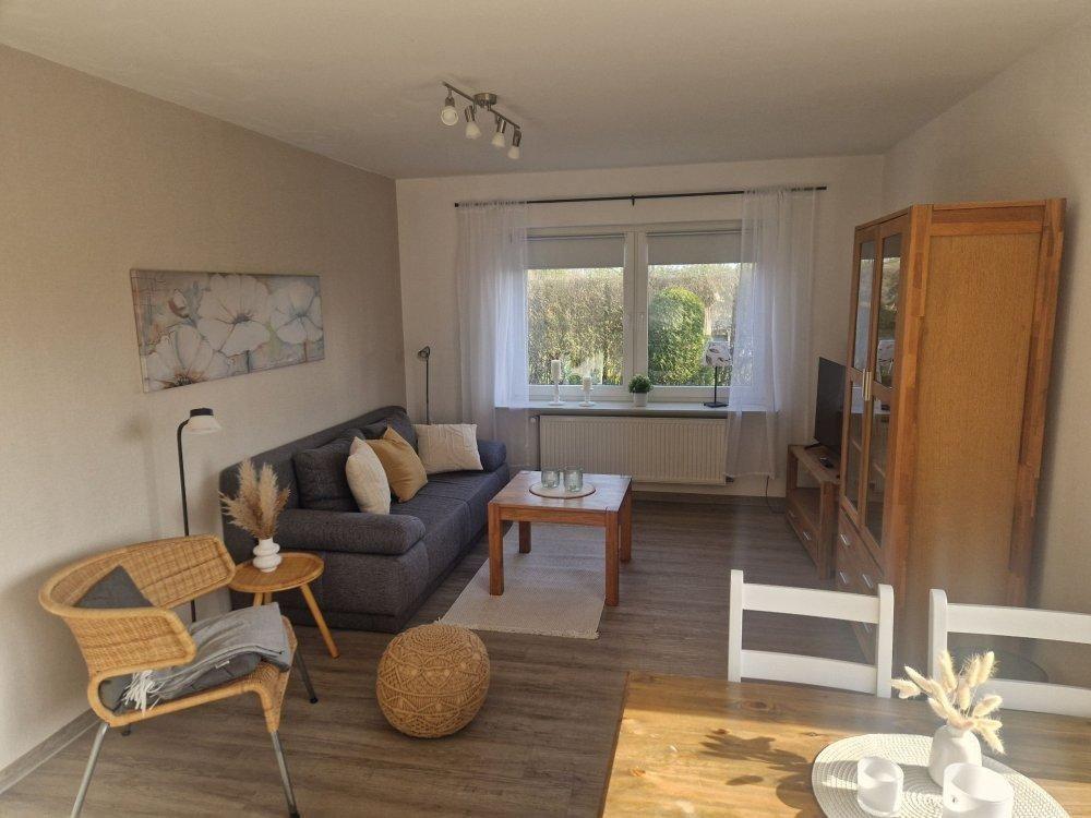 Wohnzimmer mit Sofa, Tisch, Stuhl und Fenster. Holzmöbel und Wandbild.