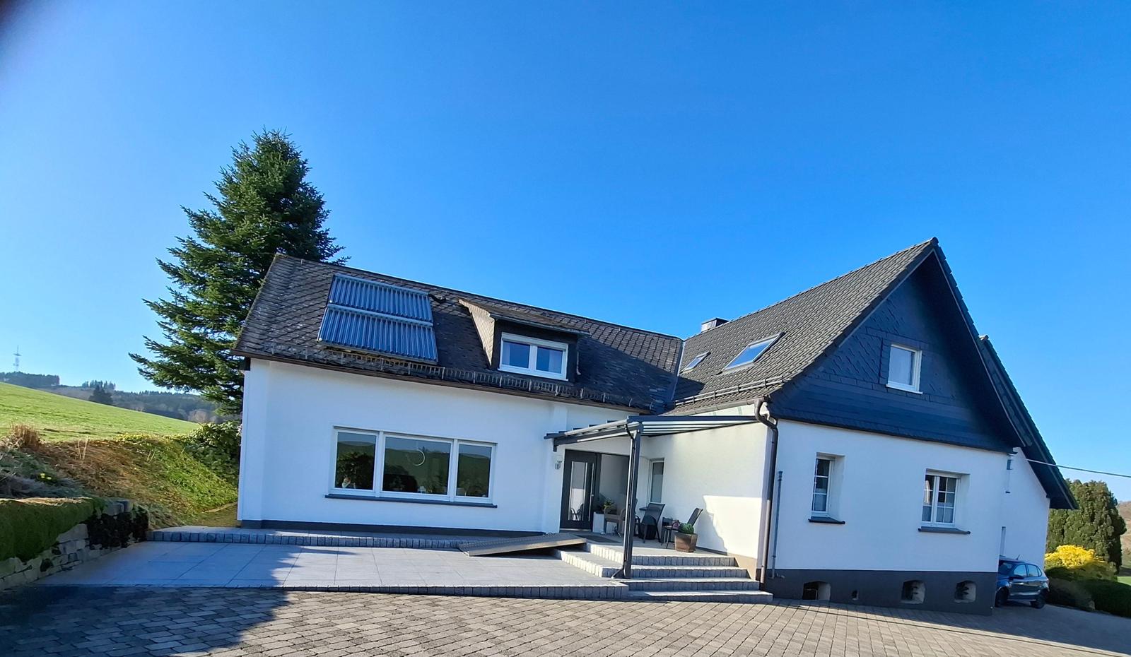 Hauseingang mit Überdachung und Sonnenterrasse im Grünen