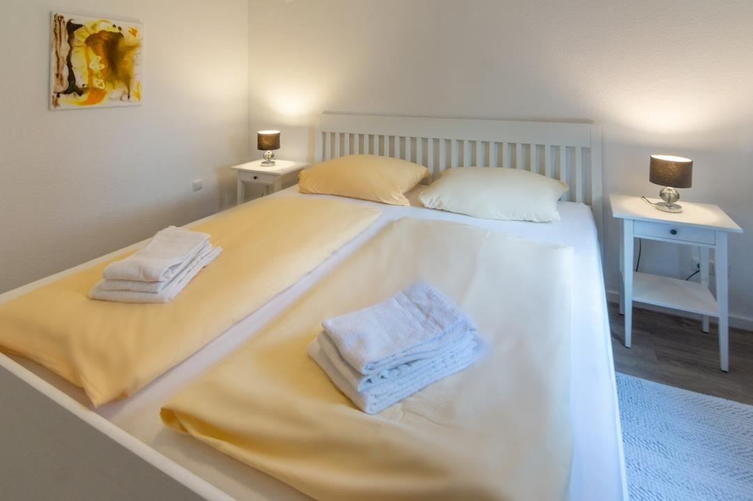 Schlafzimmer mit Doppelbett, zwei Nachttischen und Bettwäsche.