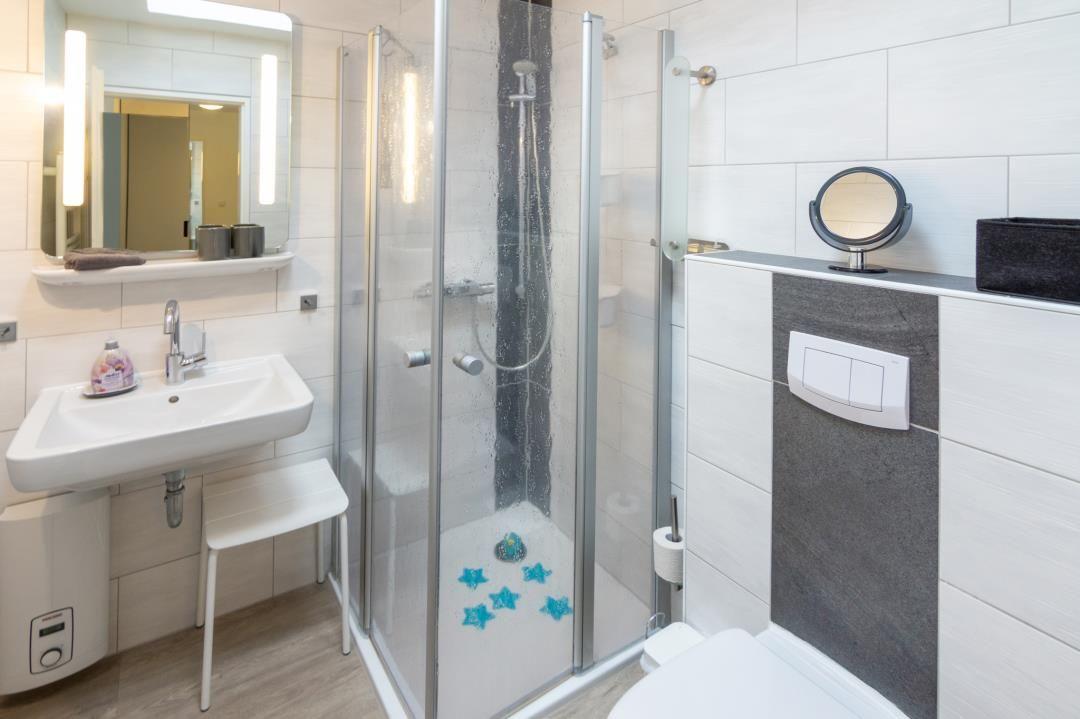 Badezimmer mit Dusche, Waschbecken und Toilette.
