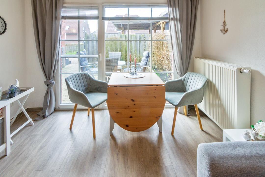Esszimmer mit Tisch und zwei Stühlen, Blick auf Garten durch Glasfront.
