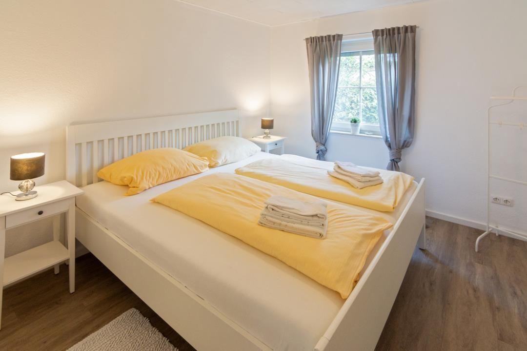 Schlafzimmer mit Doppelbett, Fenster und Nachttischen.