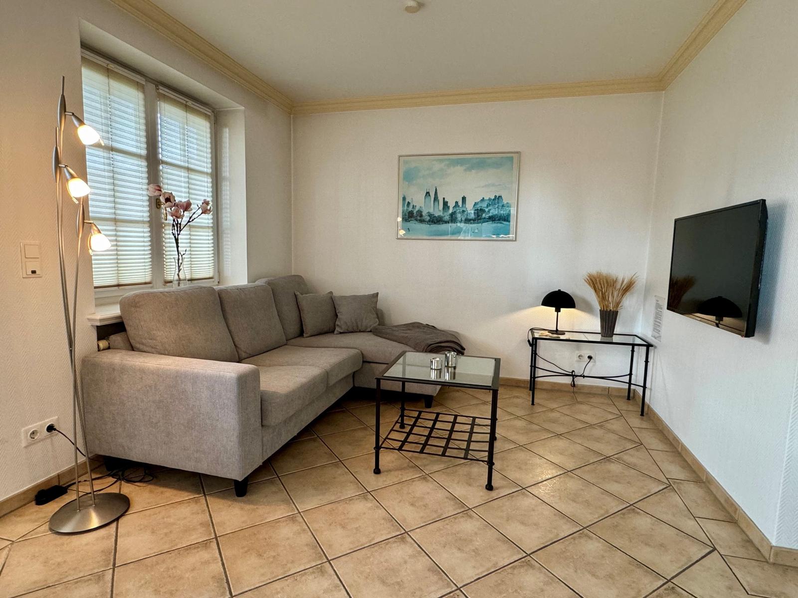 Wohnzimmer mit Sofa, Couchtisch und Fernseher an der Wand.