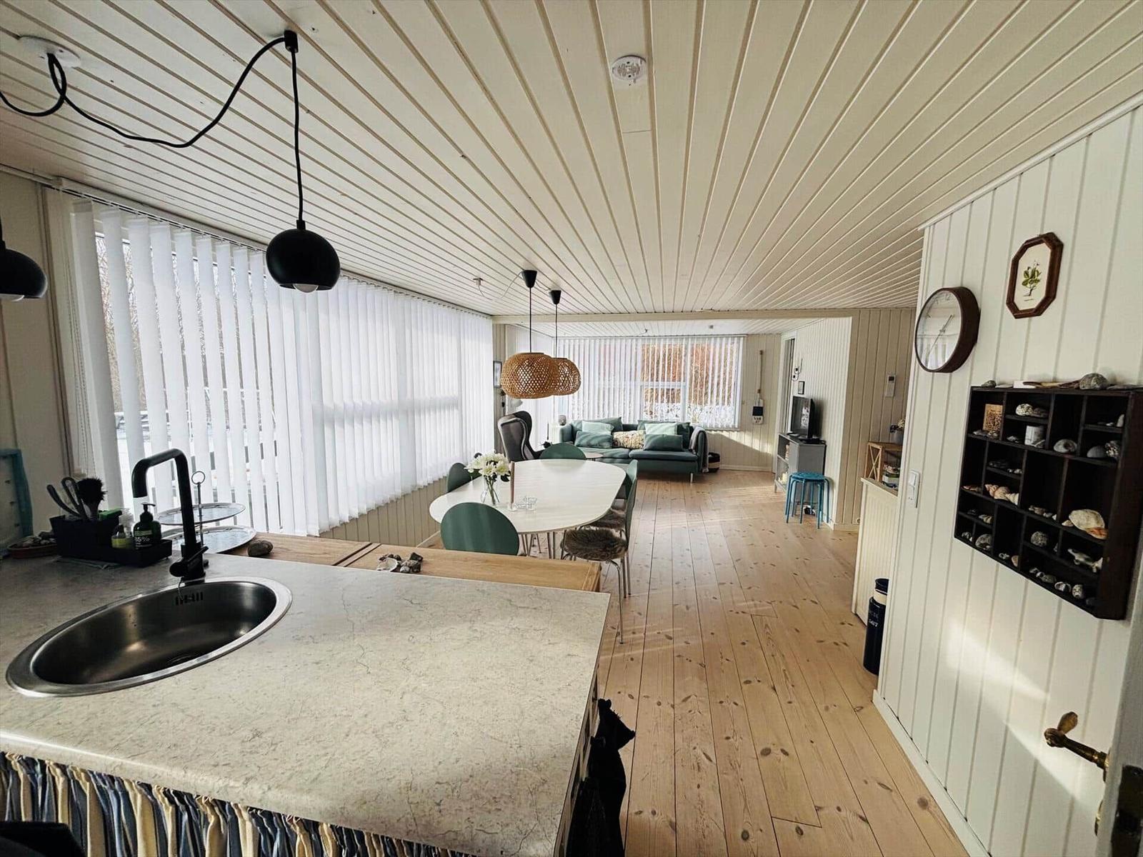 Küche mit Essbereich und Wohnzimmer mit Holzboden und weißen Wänden.