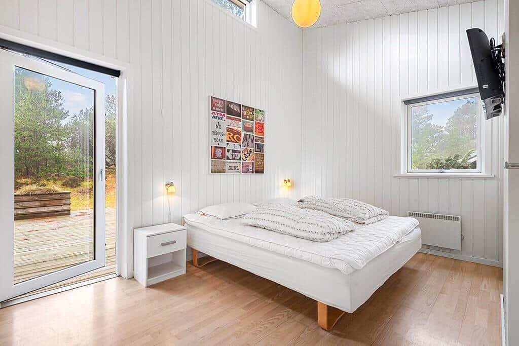 Schlafzimmer mit Bett, Fenster und Tür zur Terrasse.