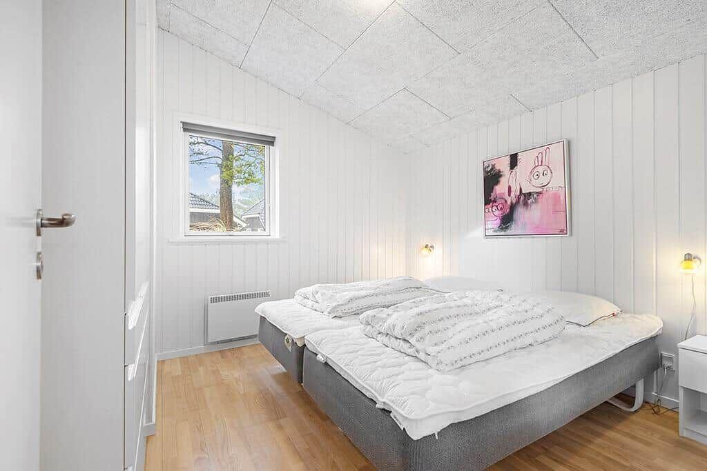 Schlafzimmer mit Doppelbett, Fenster und Wandbild.