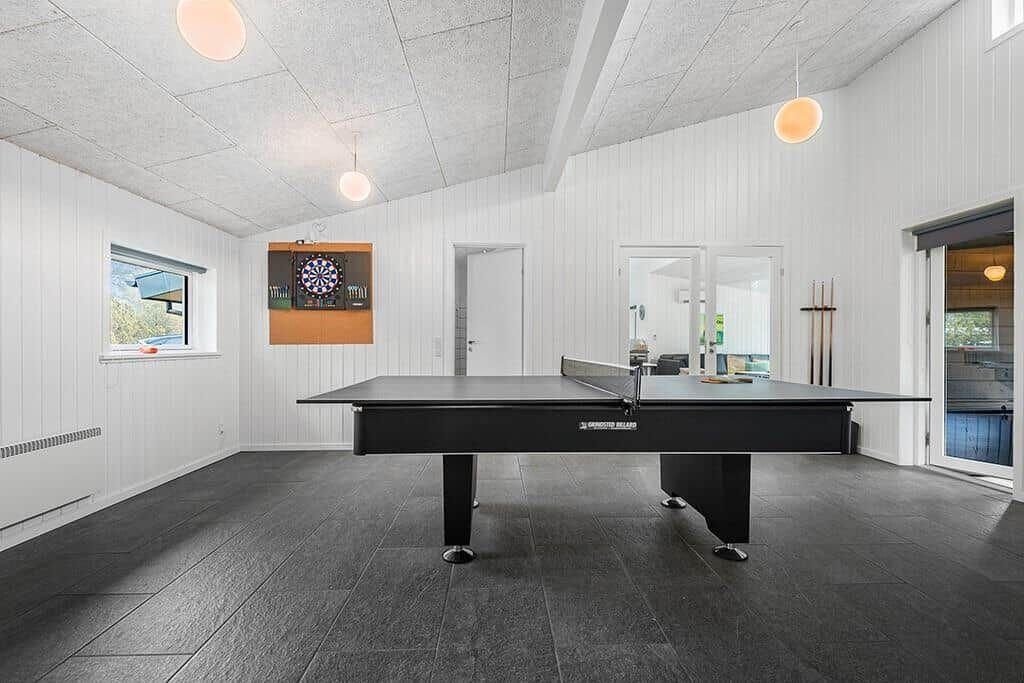 Raum mit Tischtennisplatte, Dartboard und Fensterblick auf die Landschaft.