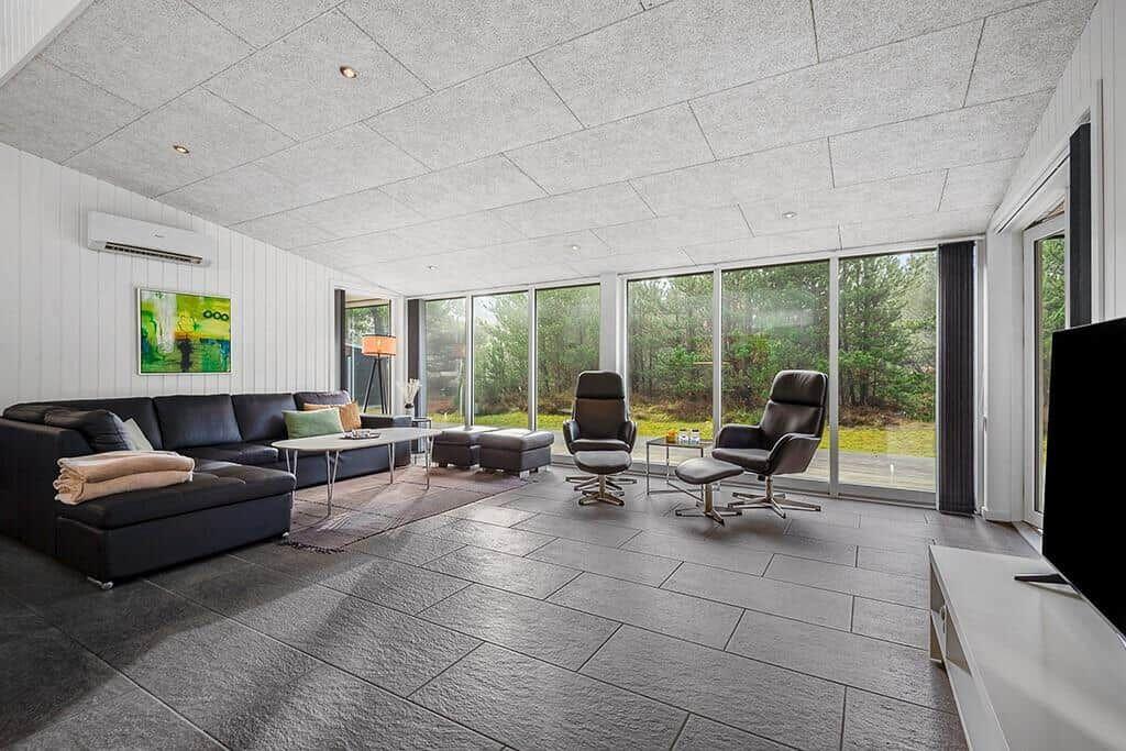 Wohnzimmer mit Sofa, zwei Sesseln und großem Fensterblick auf Garten