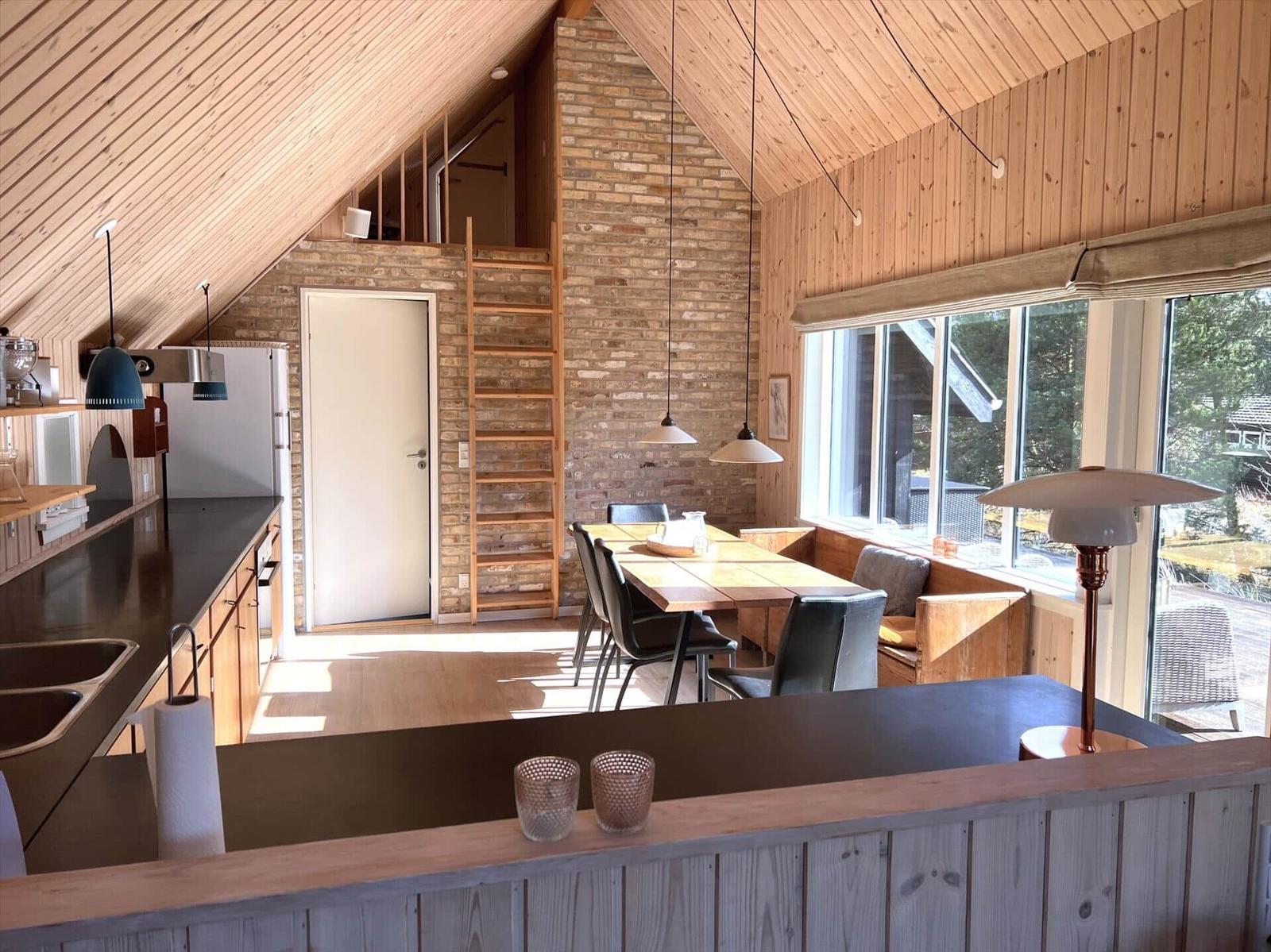 Küche, Essbereich und Wohnbereich mit Holzdecke und Steinwand.