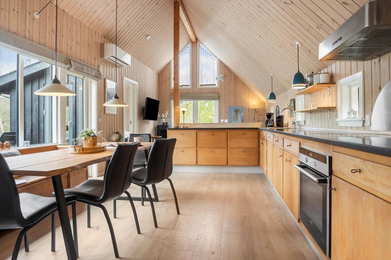Küche und Essbereich mit Holzdecke, Fenstern und moderner Ausstattung.