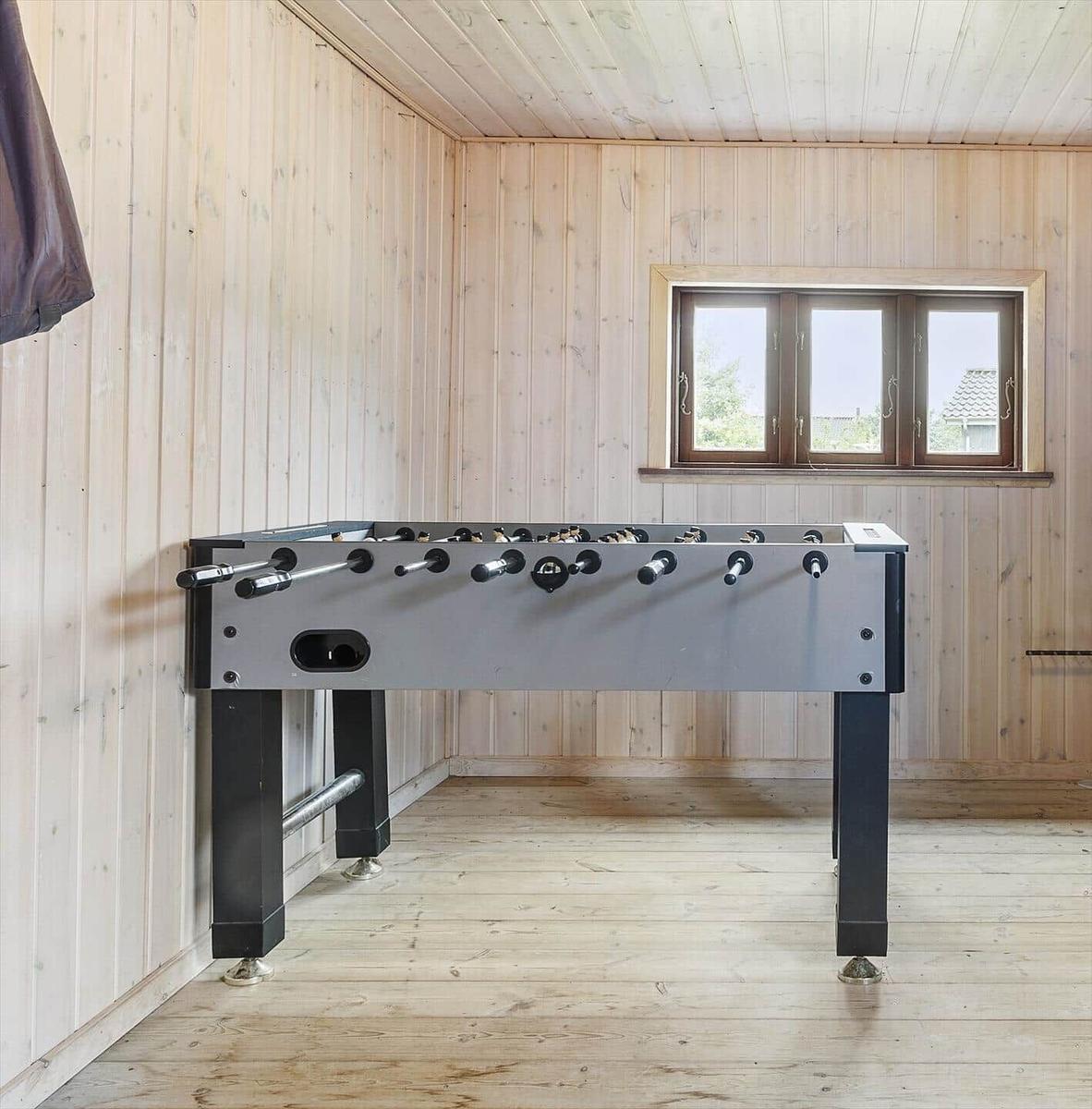 Fussballtisch in einem Holzraum mit Fenster und Holzboden.