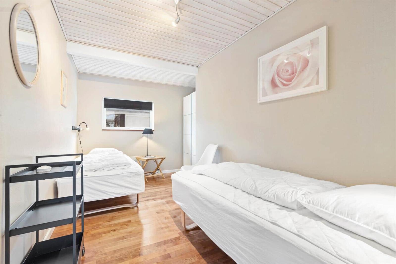 Zwei Betten, Holzboden, Wandbild und Spiegel im Schlafzimmer.