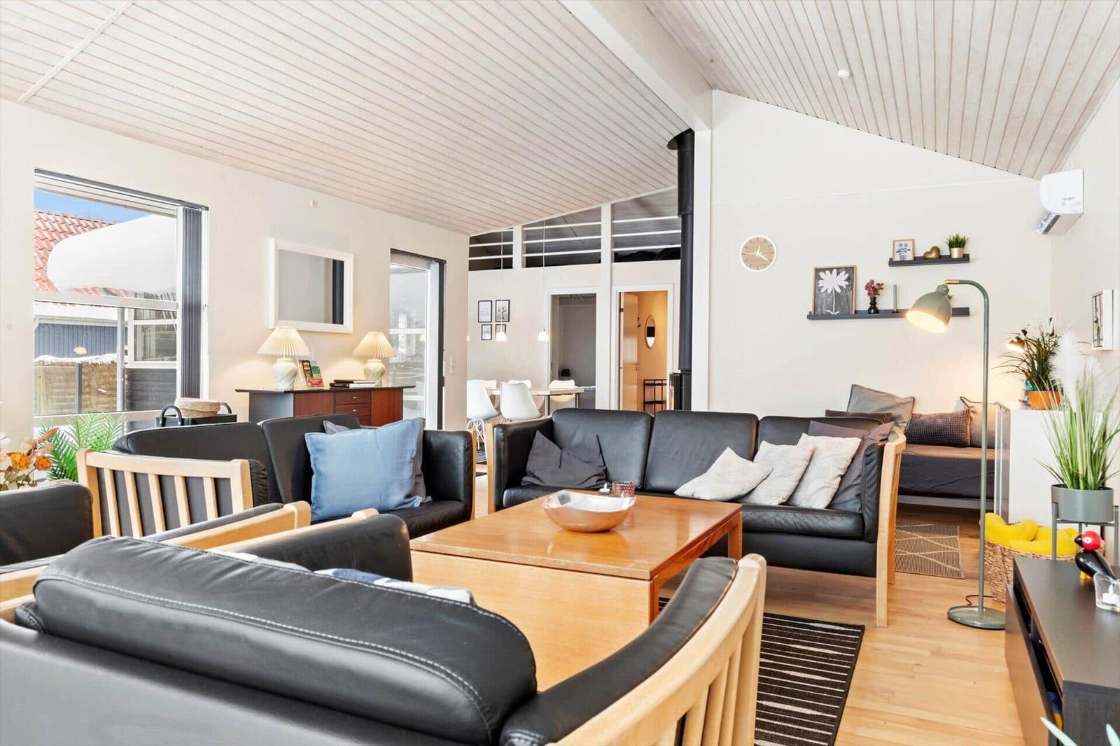 Wohnzimmer mit schwarzen Sofas, Holztisch und hohem Dach