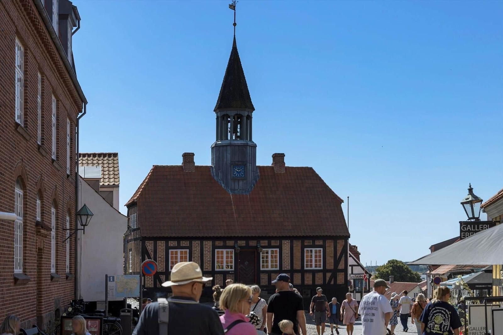 Historisches Gebäude mit Turm und Zifferblatt in einer belebten Straße.