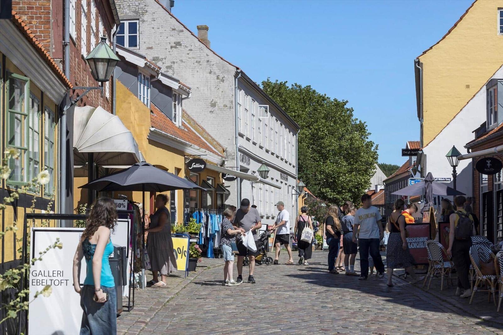Eine belebte Straße mit Geschäften und Passanten in einer historischen Altstadt.
