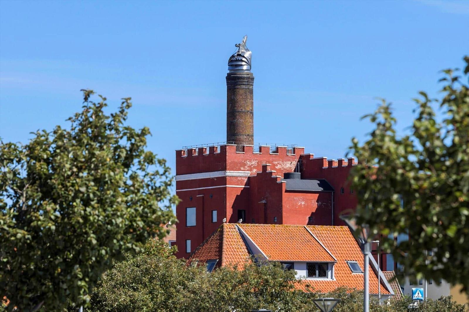 Rotes Gebäude mit Turm und Laterne, umgeben von Bäumen und einem Dach mit Ziegeln.