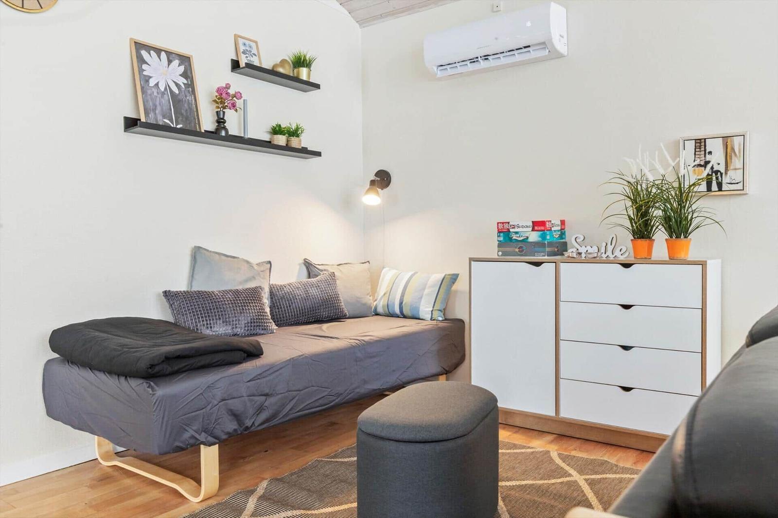 Ein Schlafzimmer mit Bett, Schrank und Wandregalen. Auf dem Bett liegen Kissen und eine Decke.