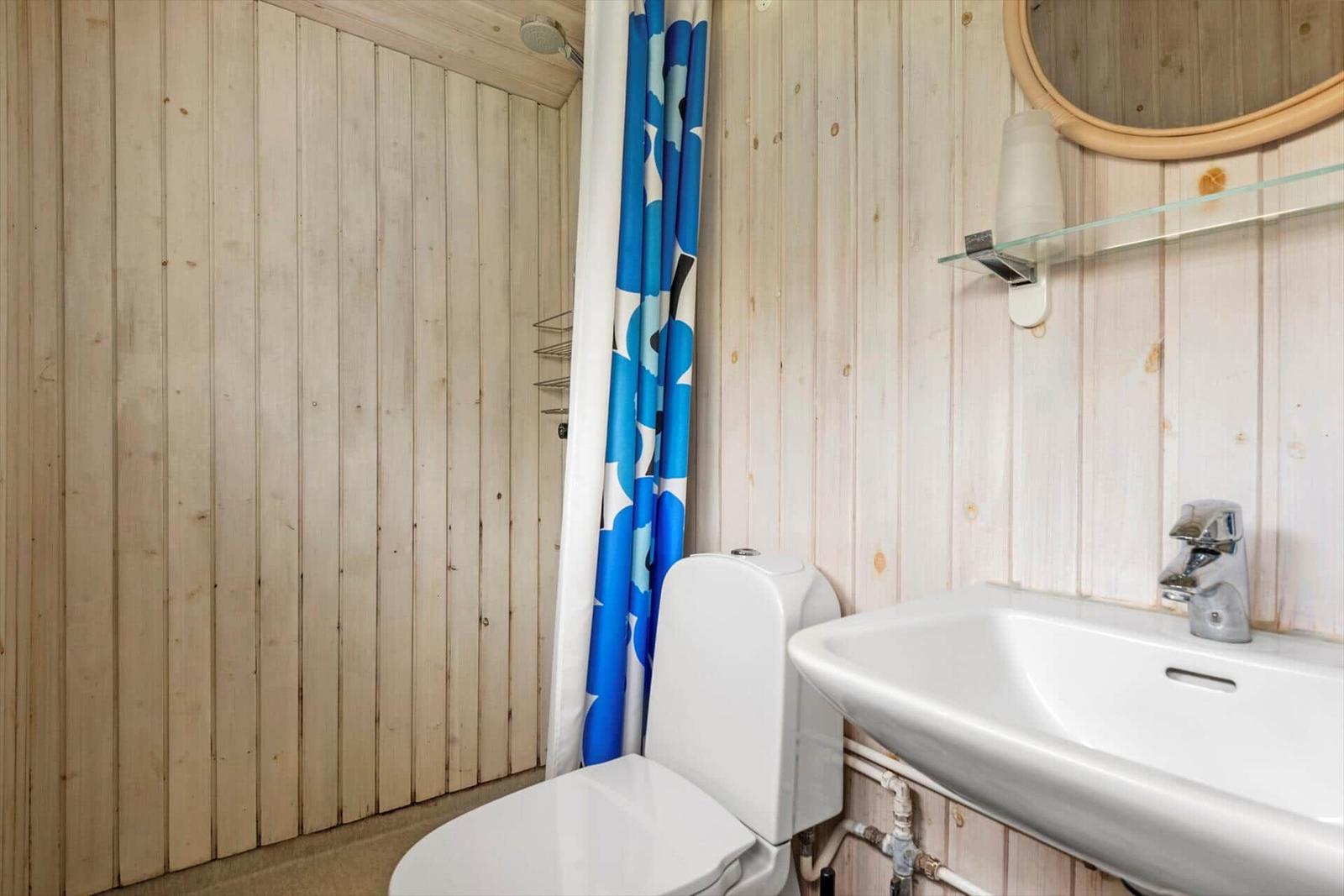 Badezimmer mit Toilette, Waschbecken und Dusche mit blauem Vorhang.