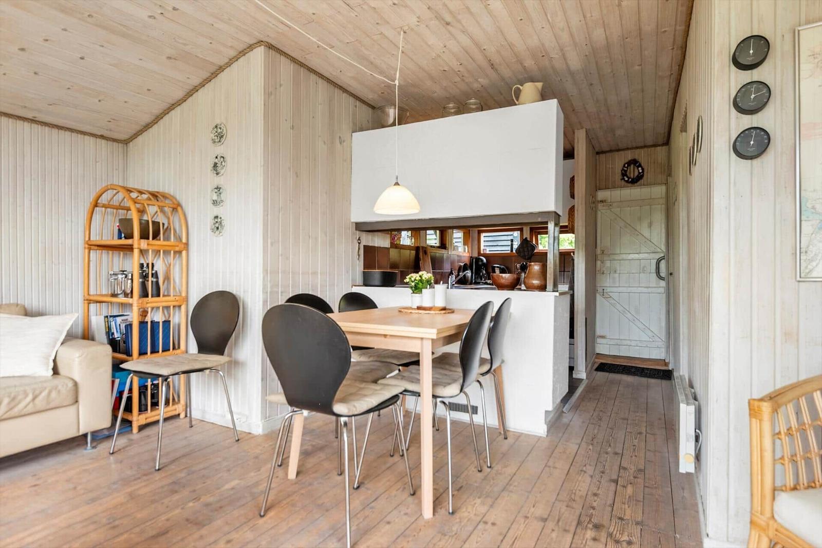 Küche mit Essbereich, Holzdecke, weiße Schränke und hölzerner Boden.