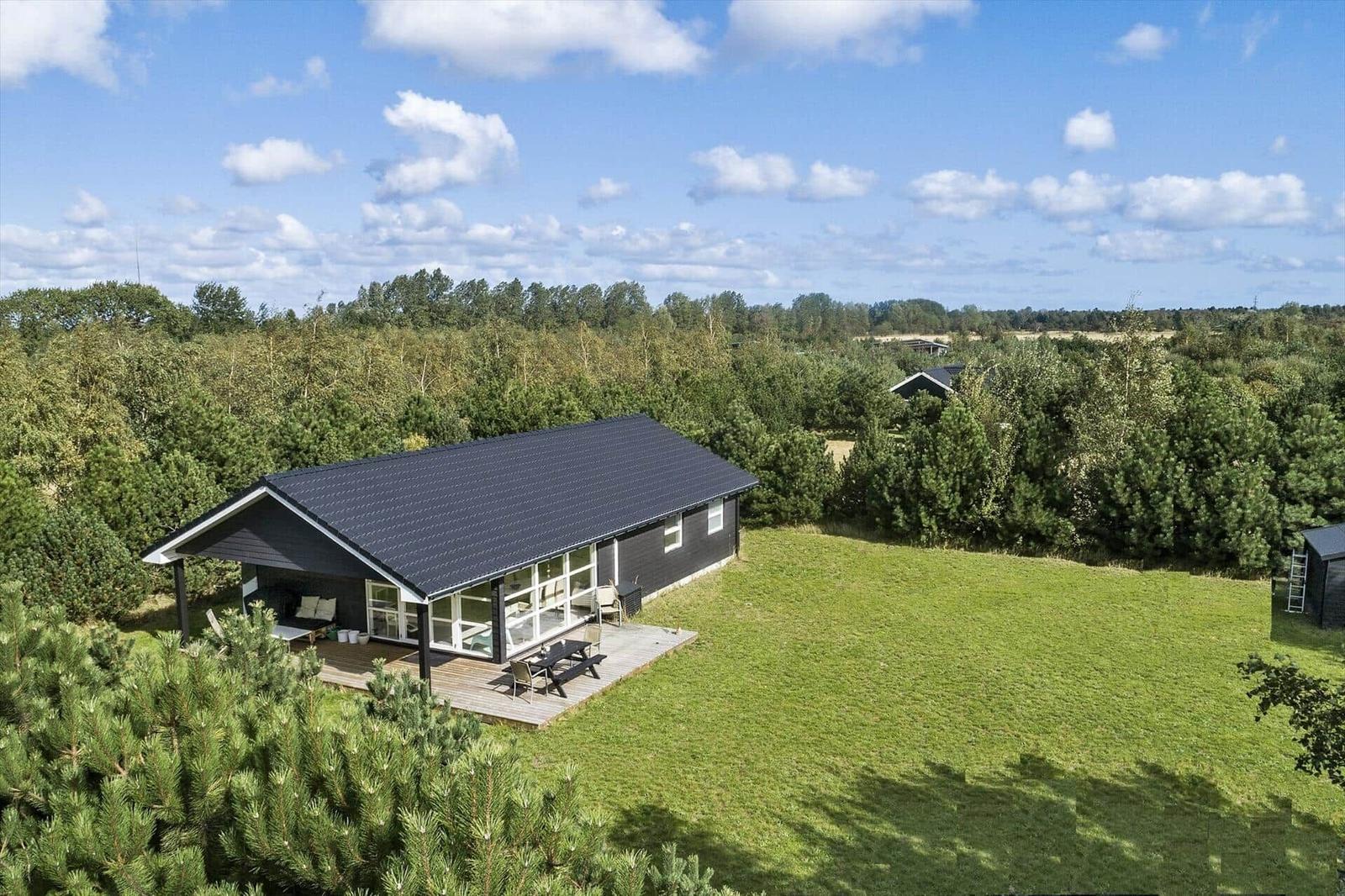 Ein modernes Haus mit Terrasse und Grillplatz in einer grünen Umgebung.