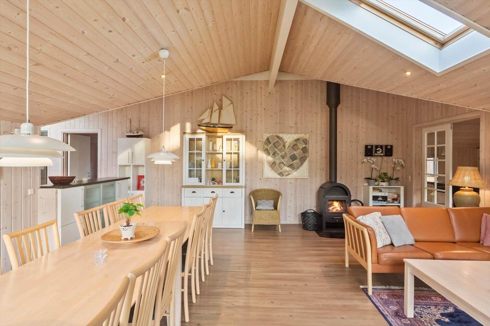 Wohn- und Essbereich mit Holzwand, Kamin und Esstisch.