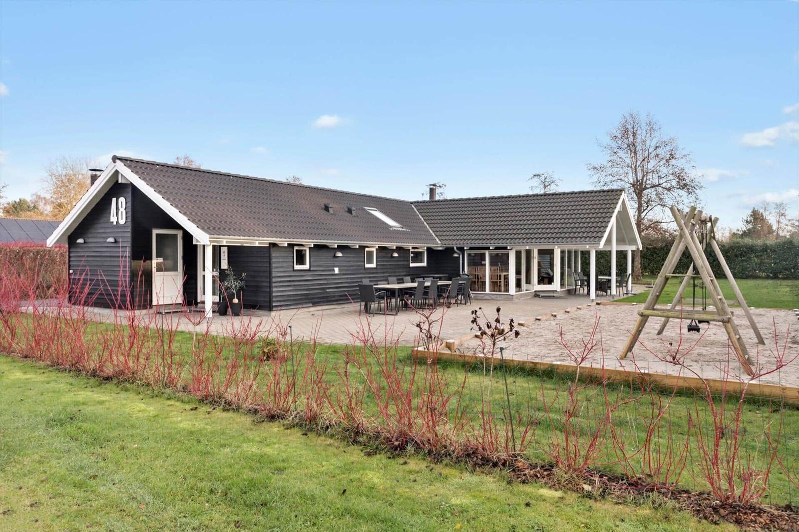Haus mit Terrasse, Garten und Spielplatz. Nummer 48. Modernes Design mit Holzverkleidung.