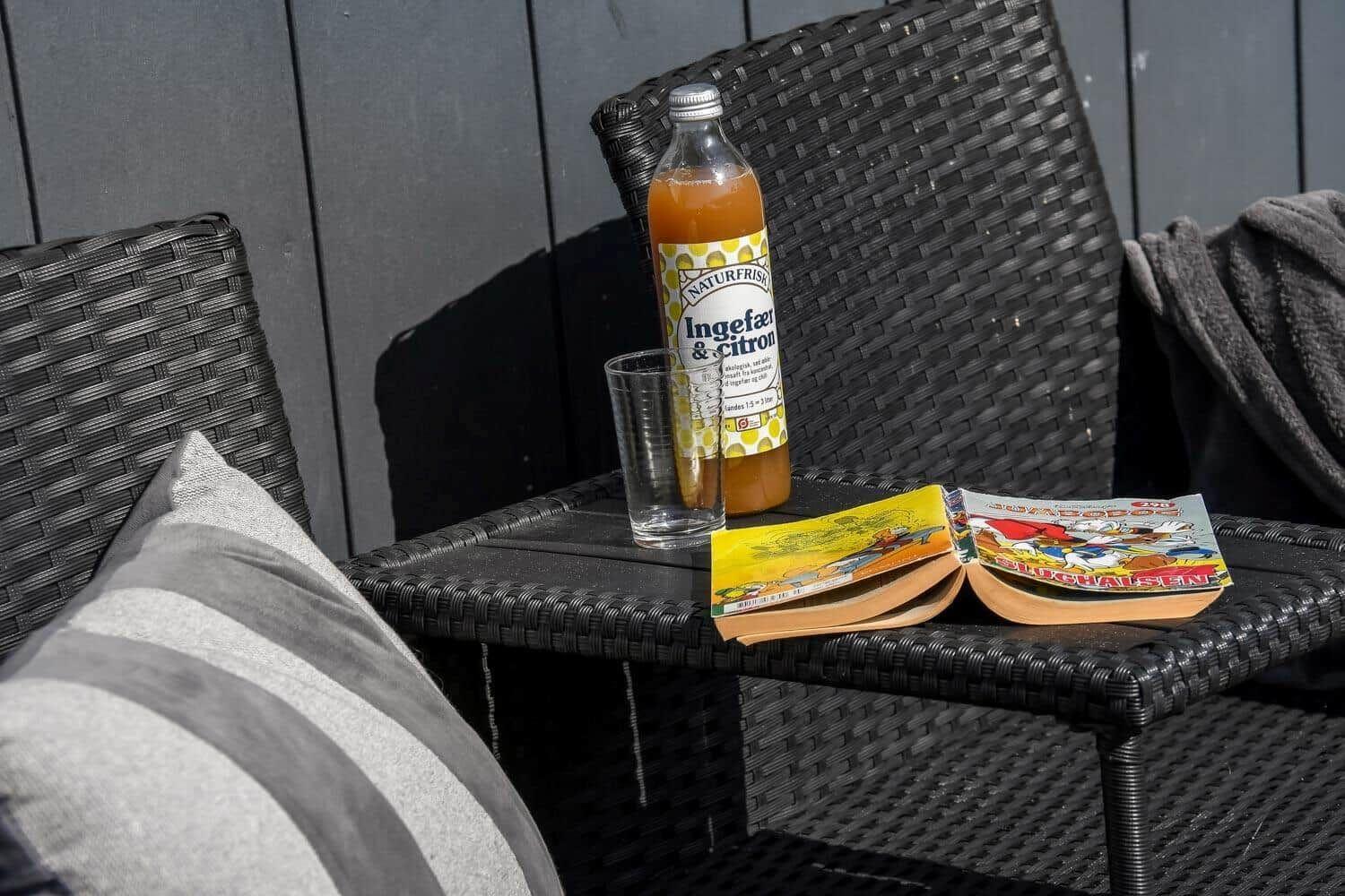 Auf der Terrasse steht ein Getränk und ein geöffnetes Buch auf einem Stuhl.