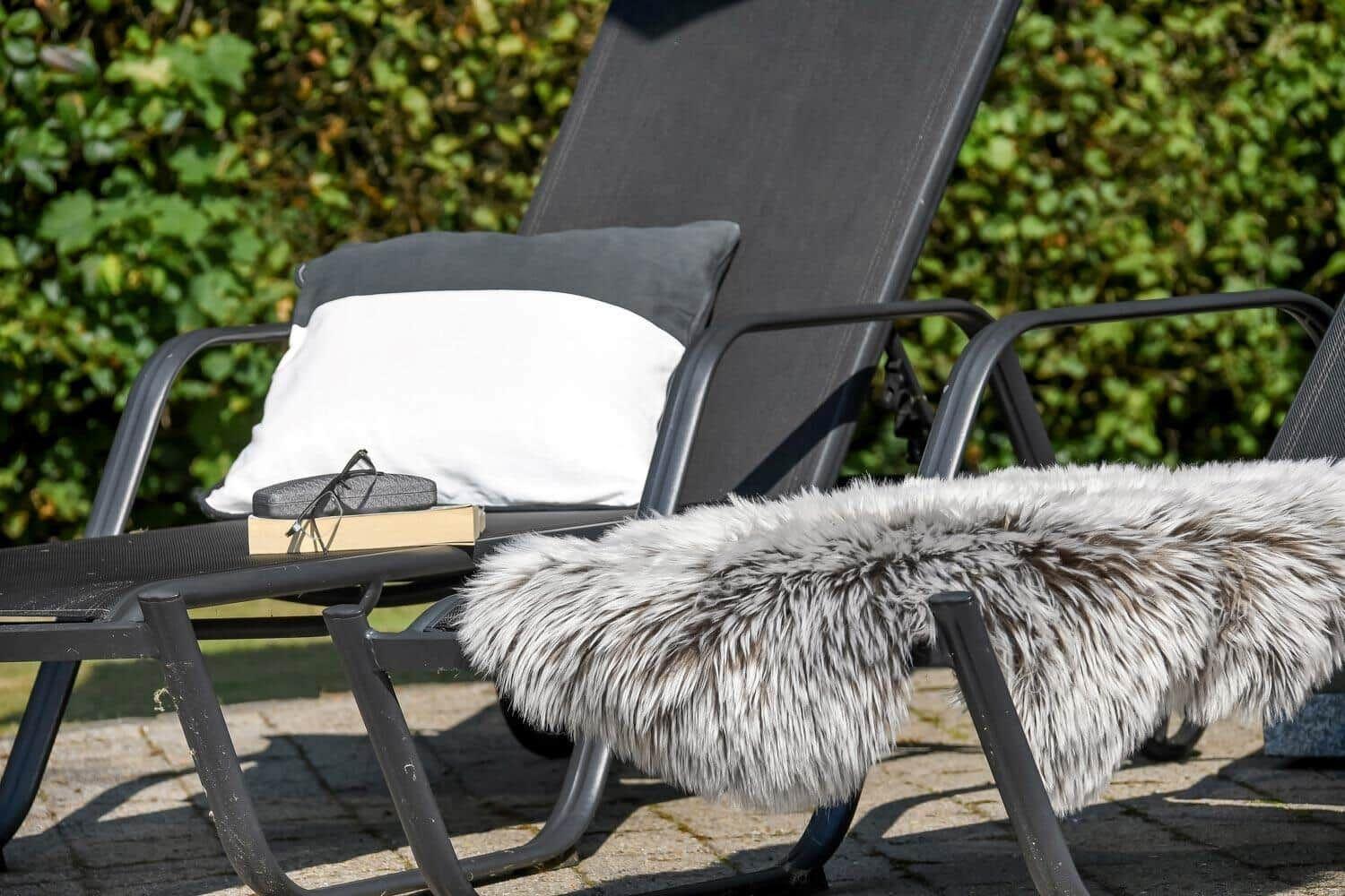Schwarze Liegestühle mit Kissen und Felldecke auf Terrasse