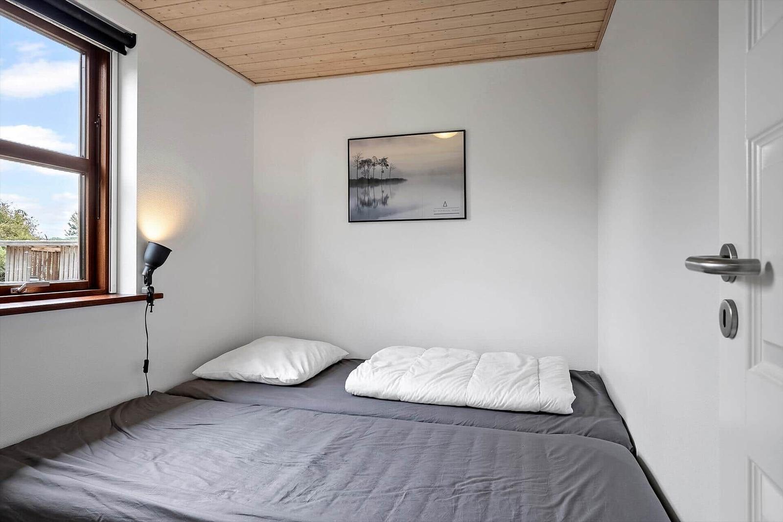 Ein Schlafzimmer mit Bett, Fenster und Wandbild.