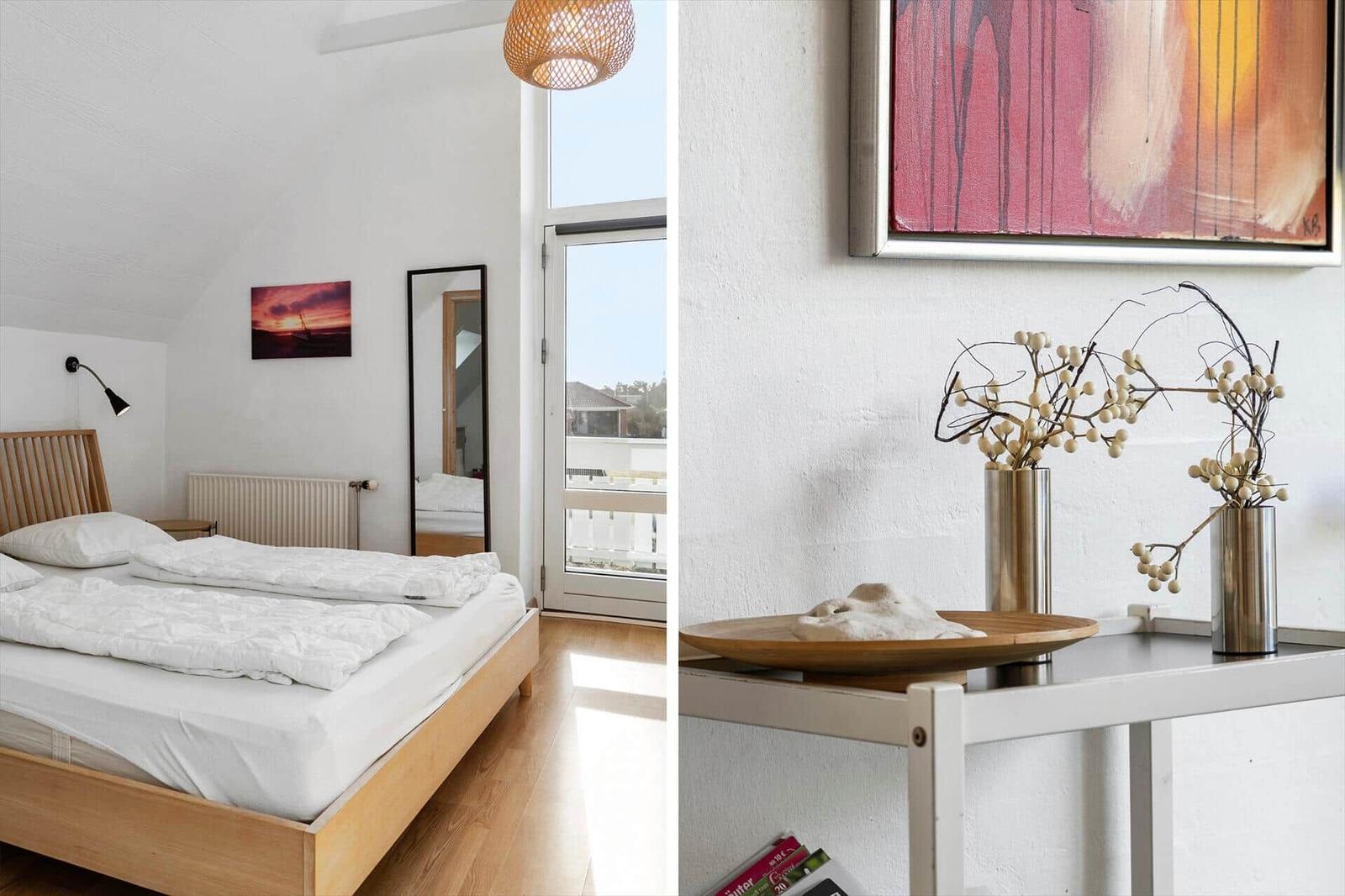 Bedroom with bed, window, and wall decor. Table with vases and artwork.