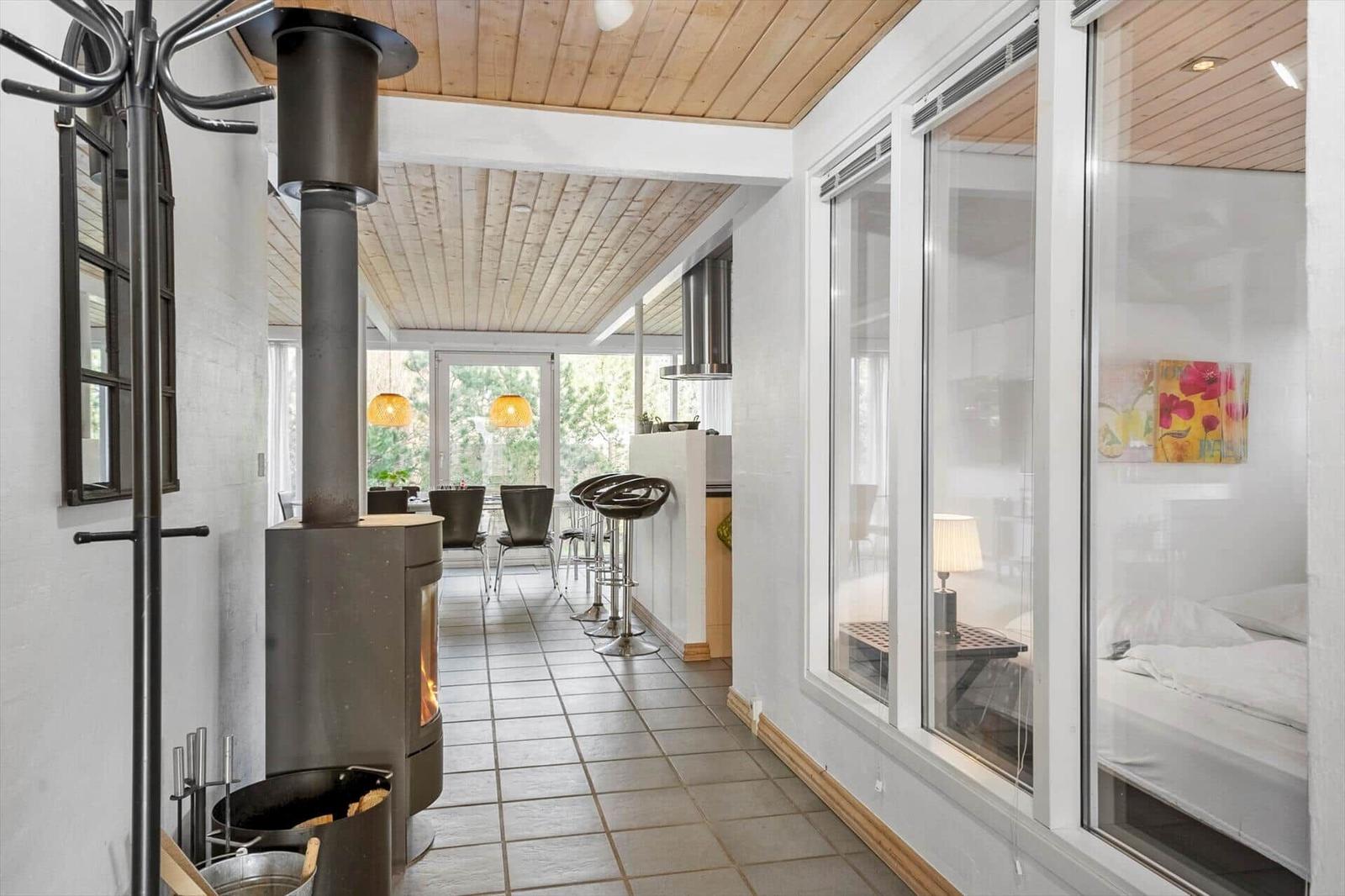 Apartment with wooden ceiling, wood stove, kitchen area, and bedroom with window.