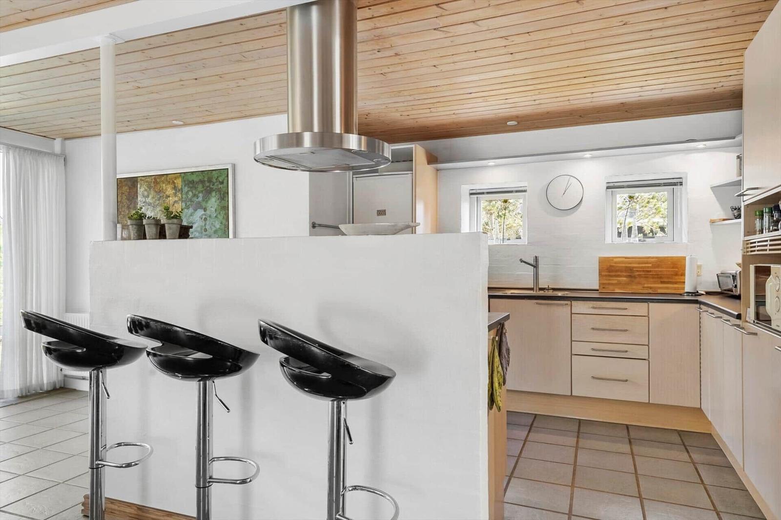Kitchen with dining area, wooden ceiling, and black bar stools.