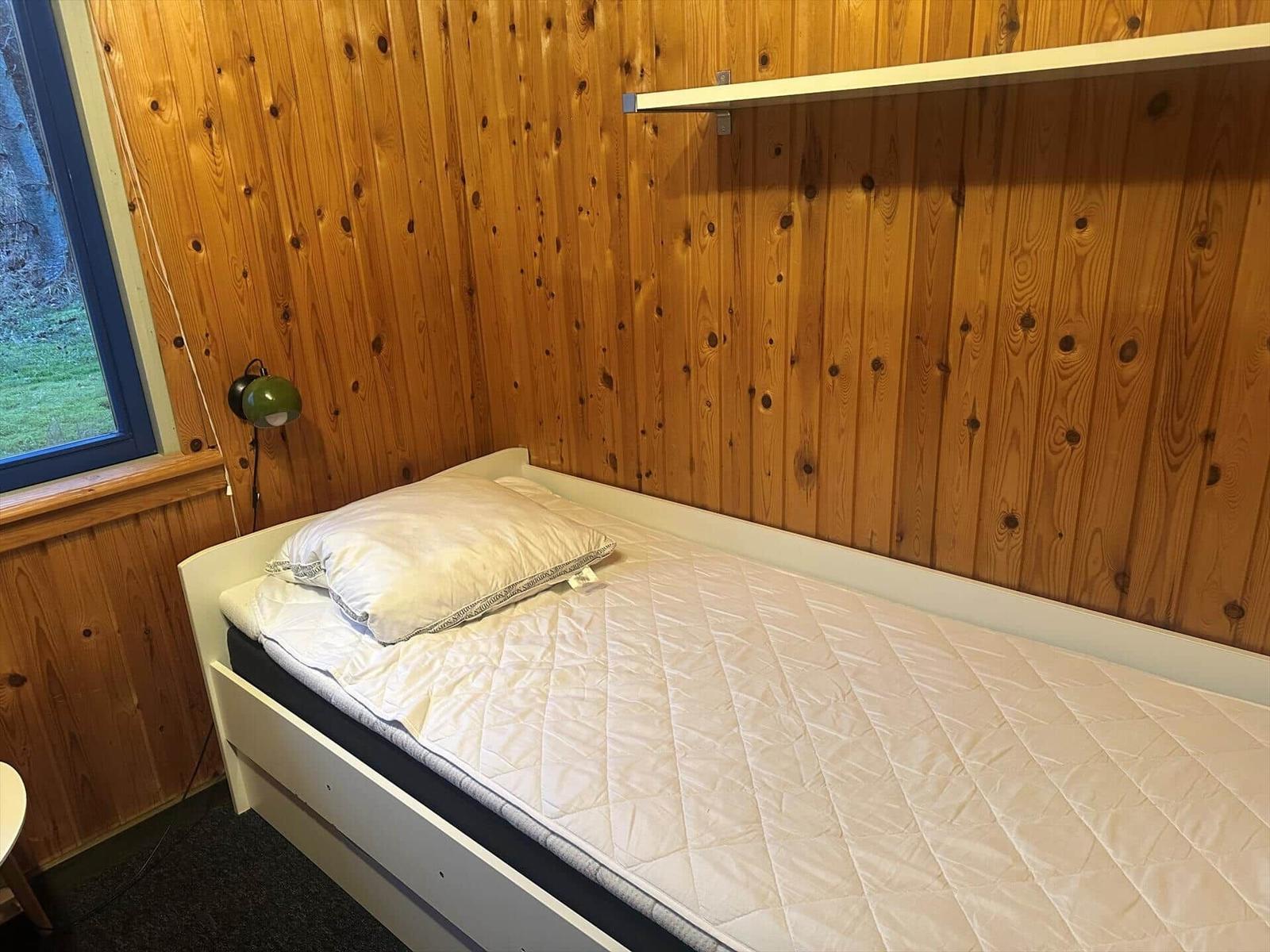 Ein Schlafzimmer mit Holzwand, Bett und Fenster.