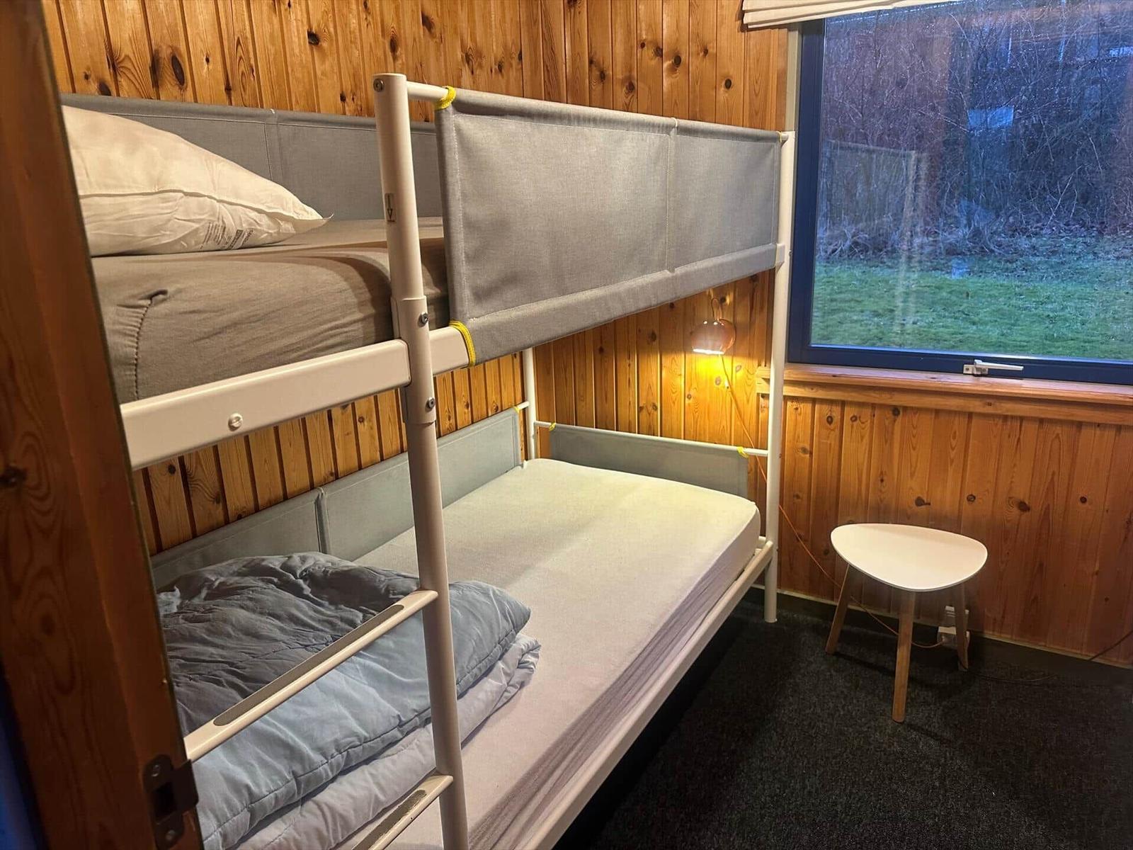 Doppelstockbett mit Matratzen und Fenster im Holzhaus.