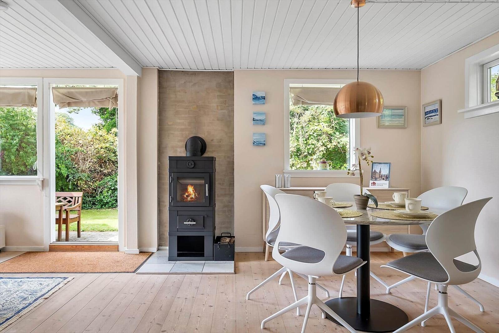 Esszimmer mit Esstisch, Stühlen und Kaminofen. Durchgang zur Terrasse mit Garten.
