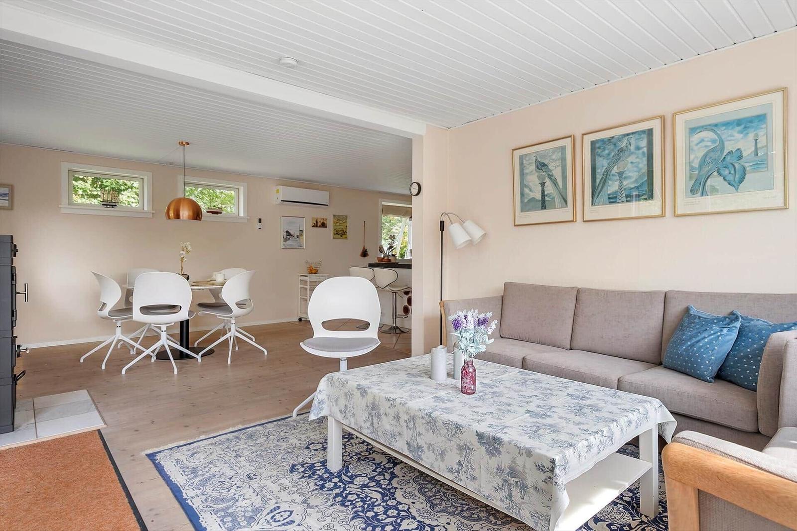 Wohn- und Essbereich mit Sofa, Tisch und Stühlen. Wandbildern und Holzboden.