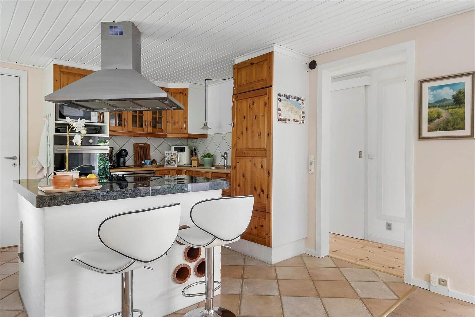 Küche mit Insel, Holzschränken und moderner Dunstabzugshaube.