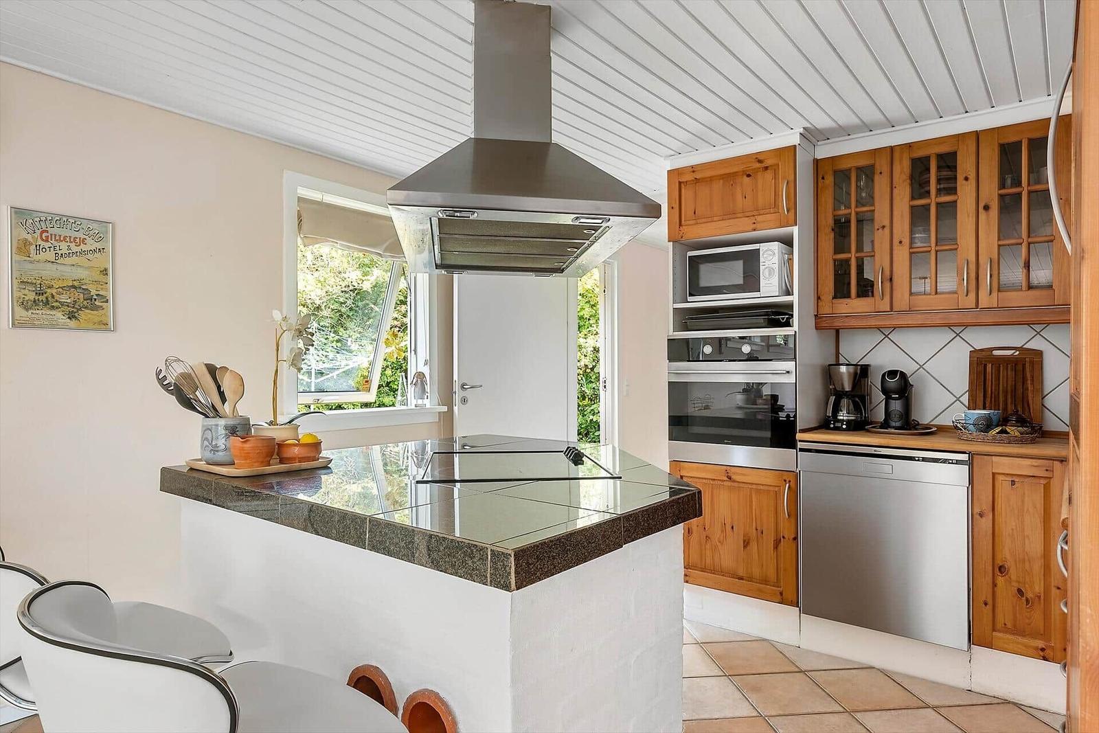 Küche mit Holzschränken, Edelstahlgeräten und Kücheninsel.