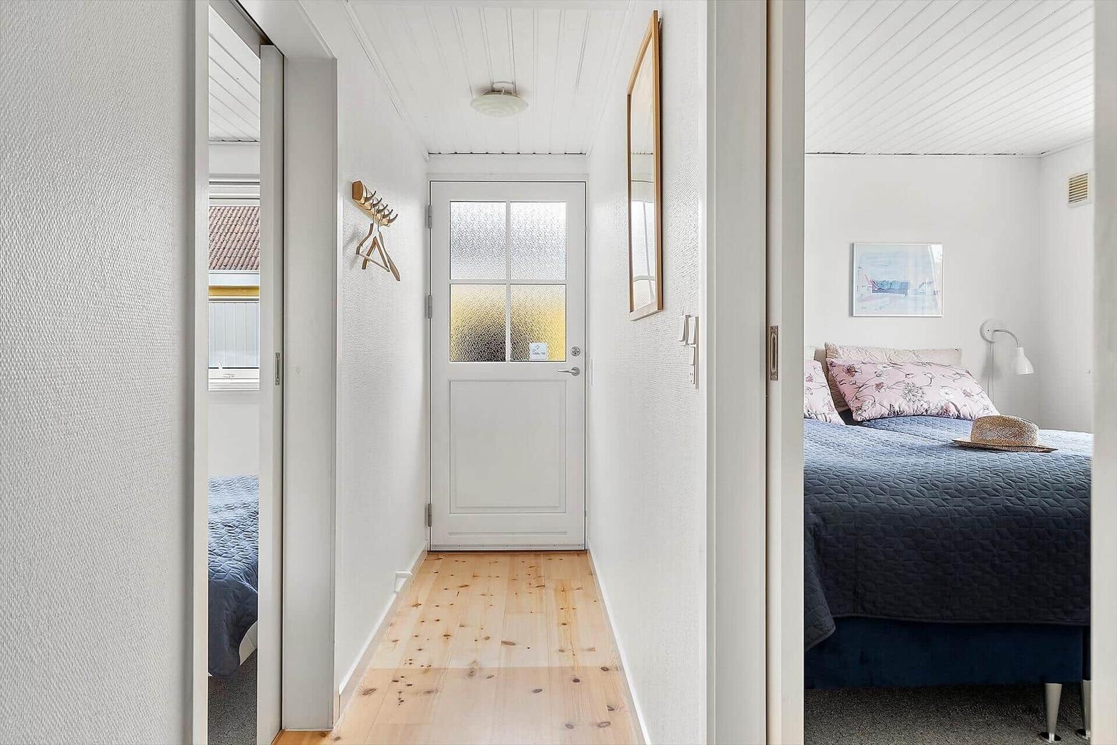 Flur mit Holzboden und Tür zu Schlafzimmer mit Bett und Wandbild