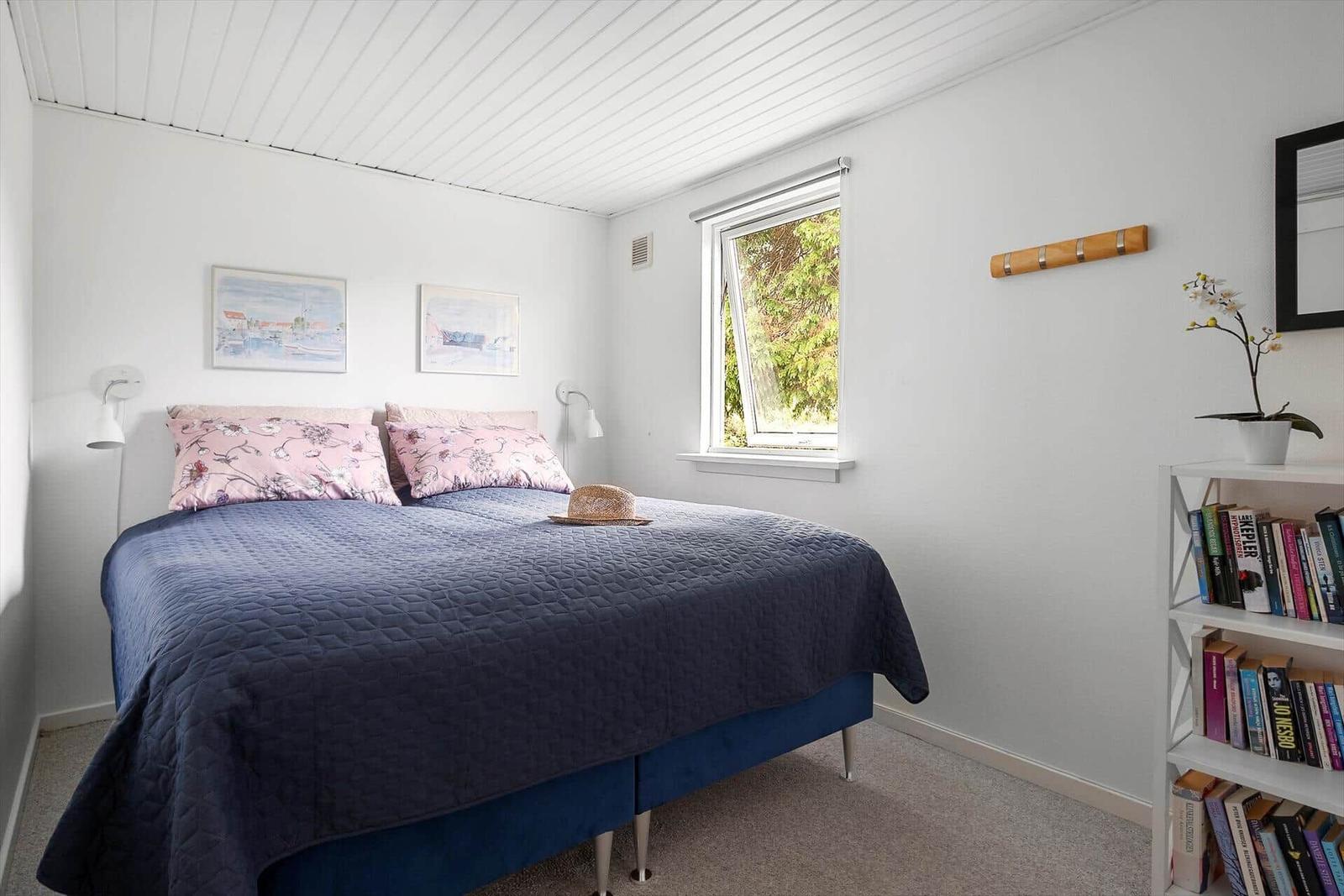 Schlafzimmer mit Bett, Fenster und Bücherregal.