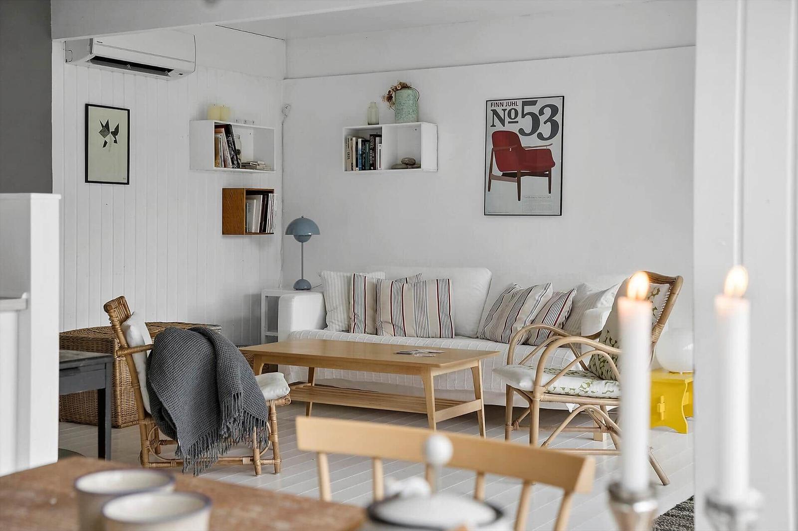 Wohnzimmer mit Sofa, Couchtisch und Stühlen. Wandregale und Poster an der Wand.