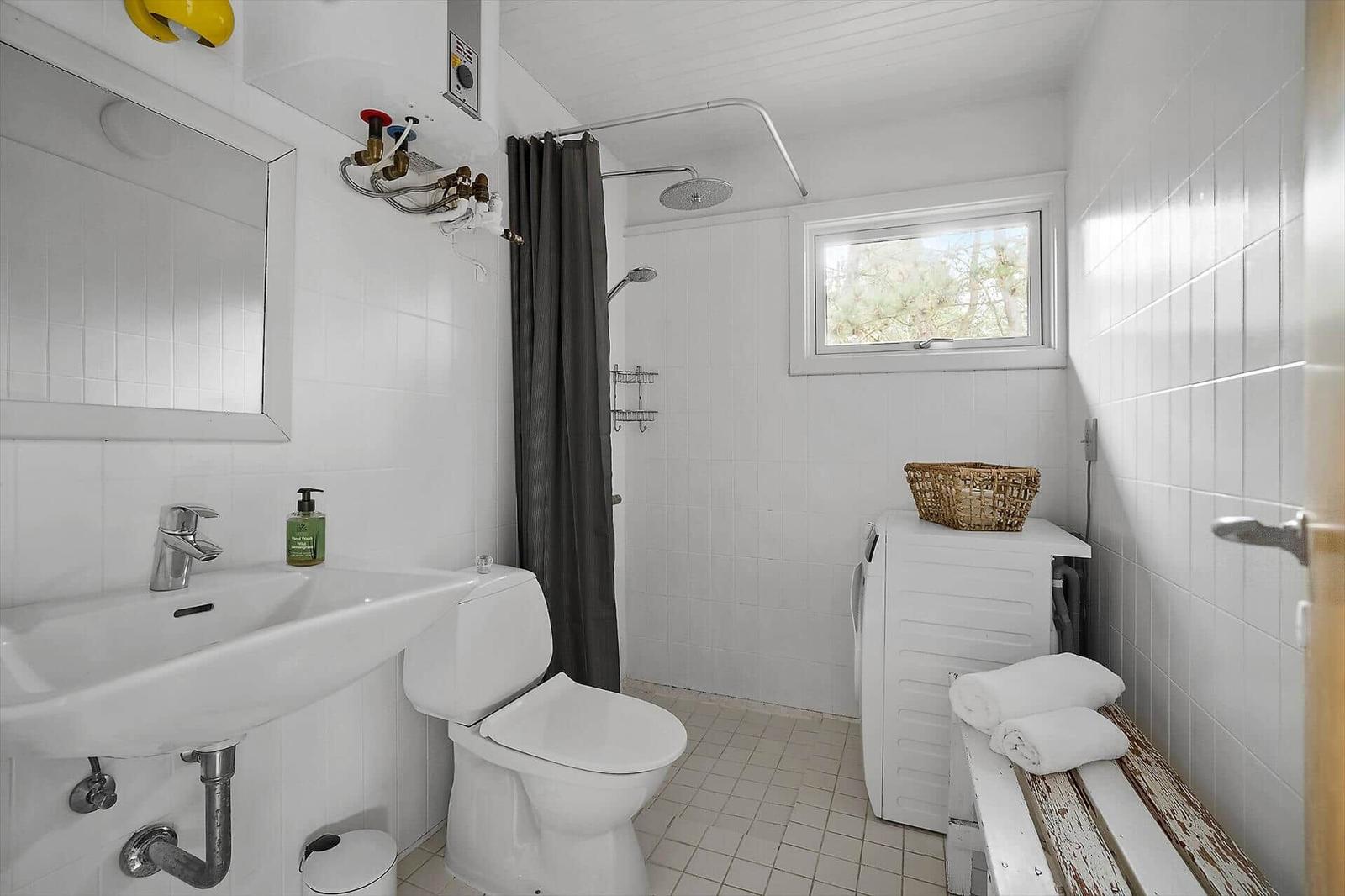 Badezimmer mit Dusche, Toilette, Waschbecken und Waschmaschine.