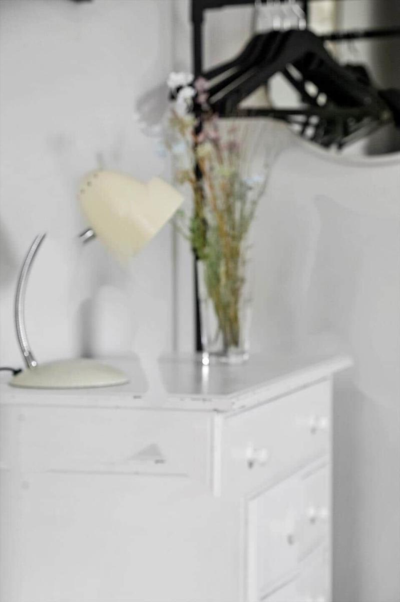 Weißer Schrank mit Lampe und Blumen auf der Oberfläche.