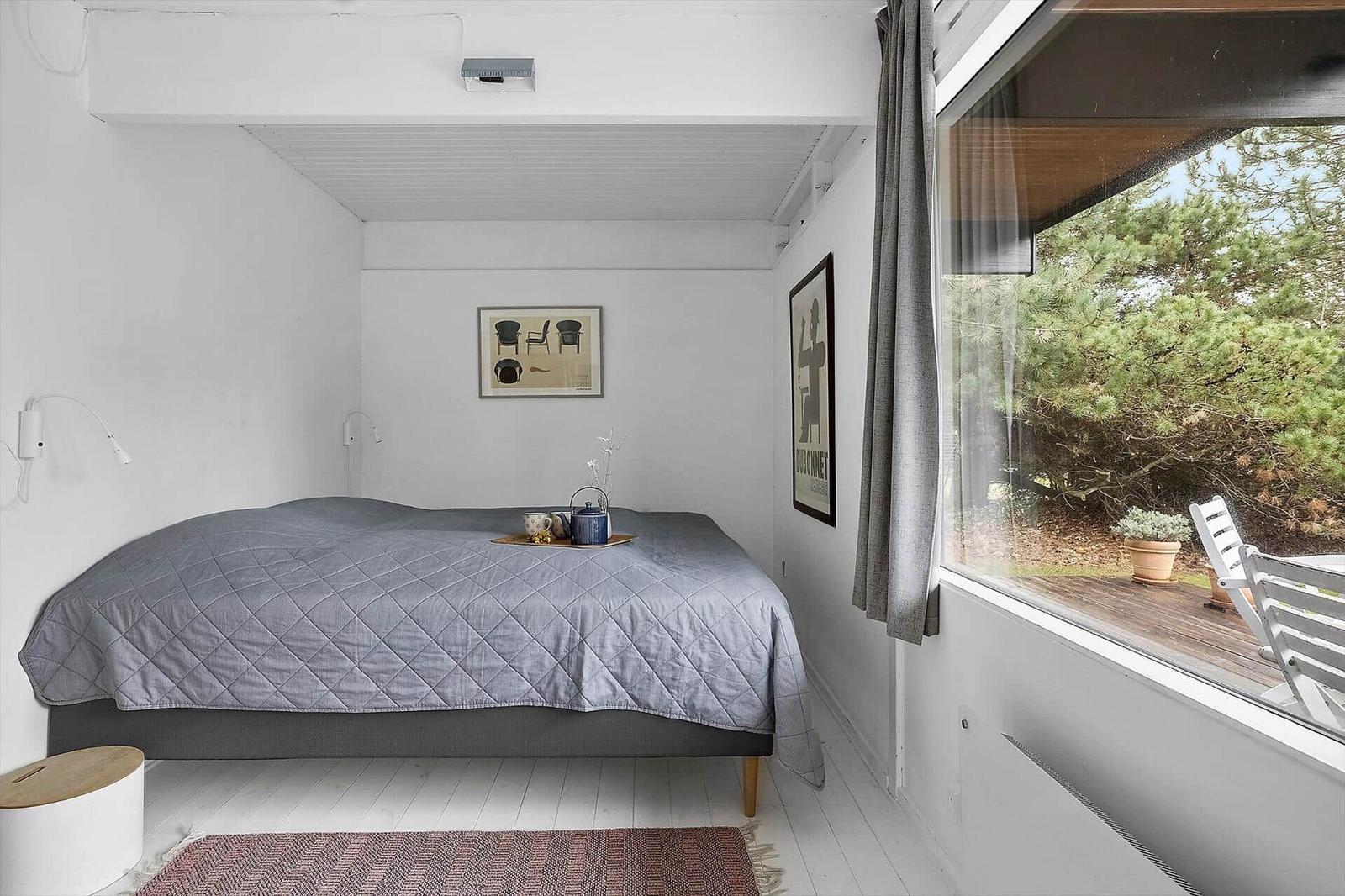 Schlafzimmer mit Bett, Fenster und Balkonansicht.