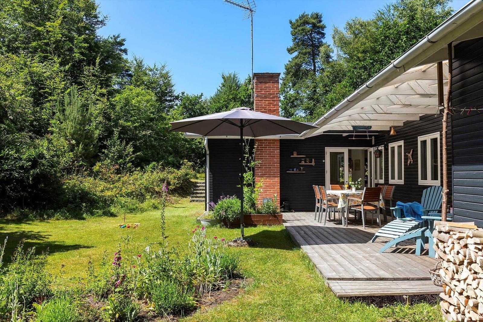 Haus mit Terrasse, Garten und Grillplatz. Holzterrasse mit Sitzgelegenheiten und Sonnenschutz.