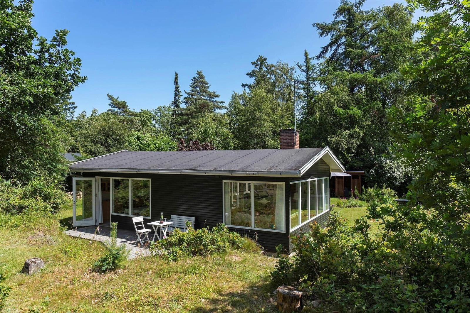 Moderne Villa mit Terrasse und Garten in grüner Umgebung.