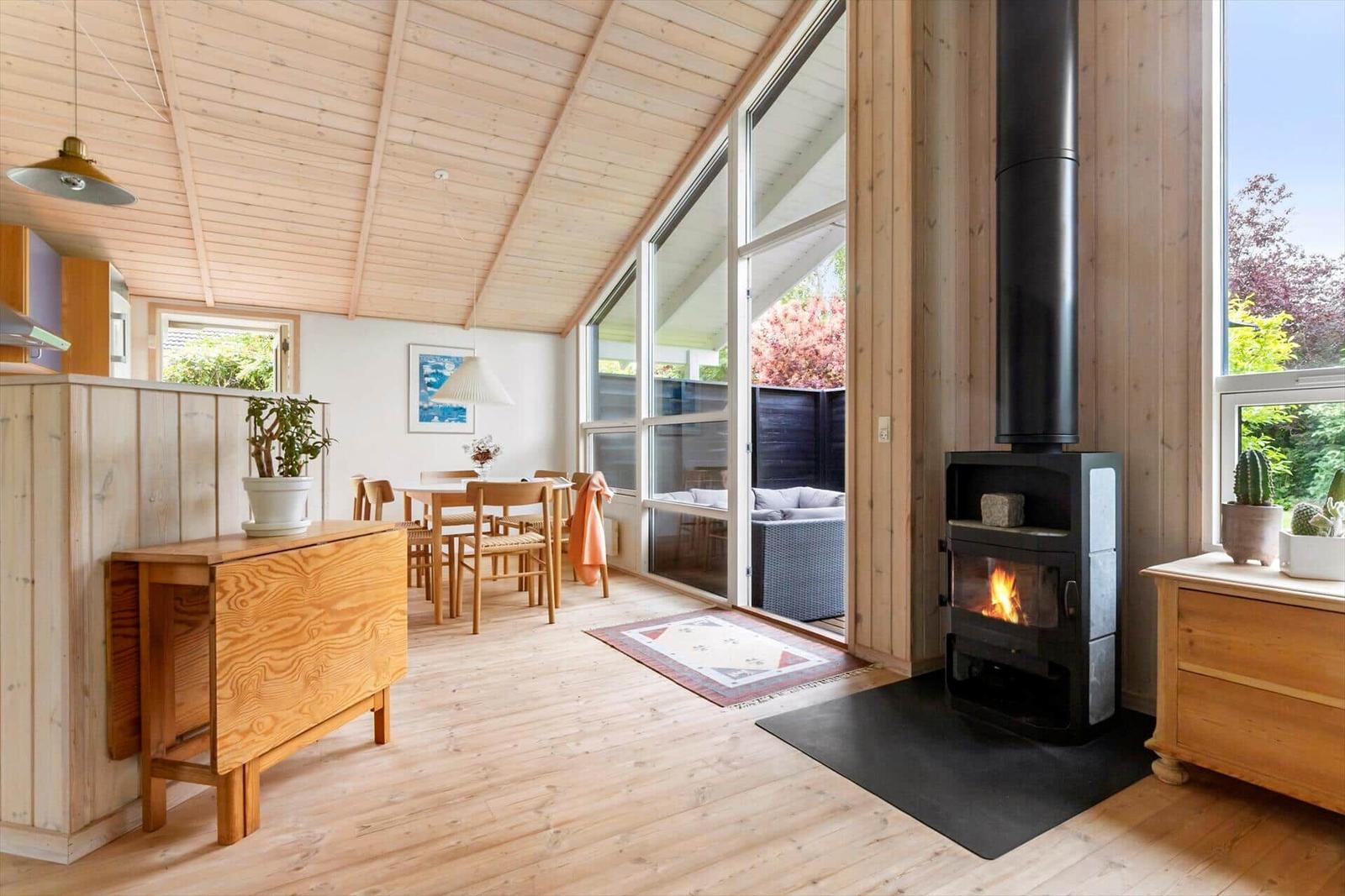 Holzgetäfelte Küche mit Esstisch, Kamin und großem Fensterblick.