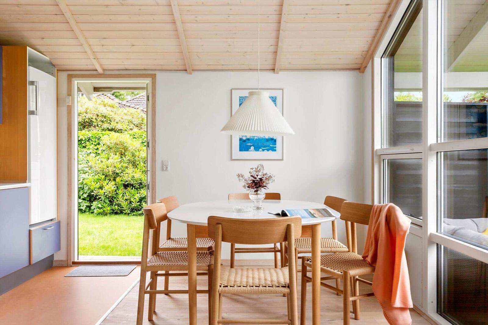 Essbereich mit runden Tisch, Holzstühlen und Blick auf Garten.