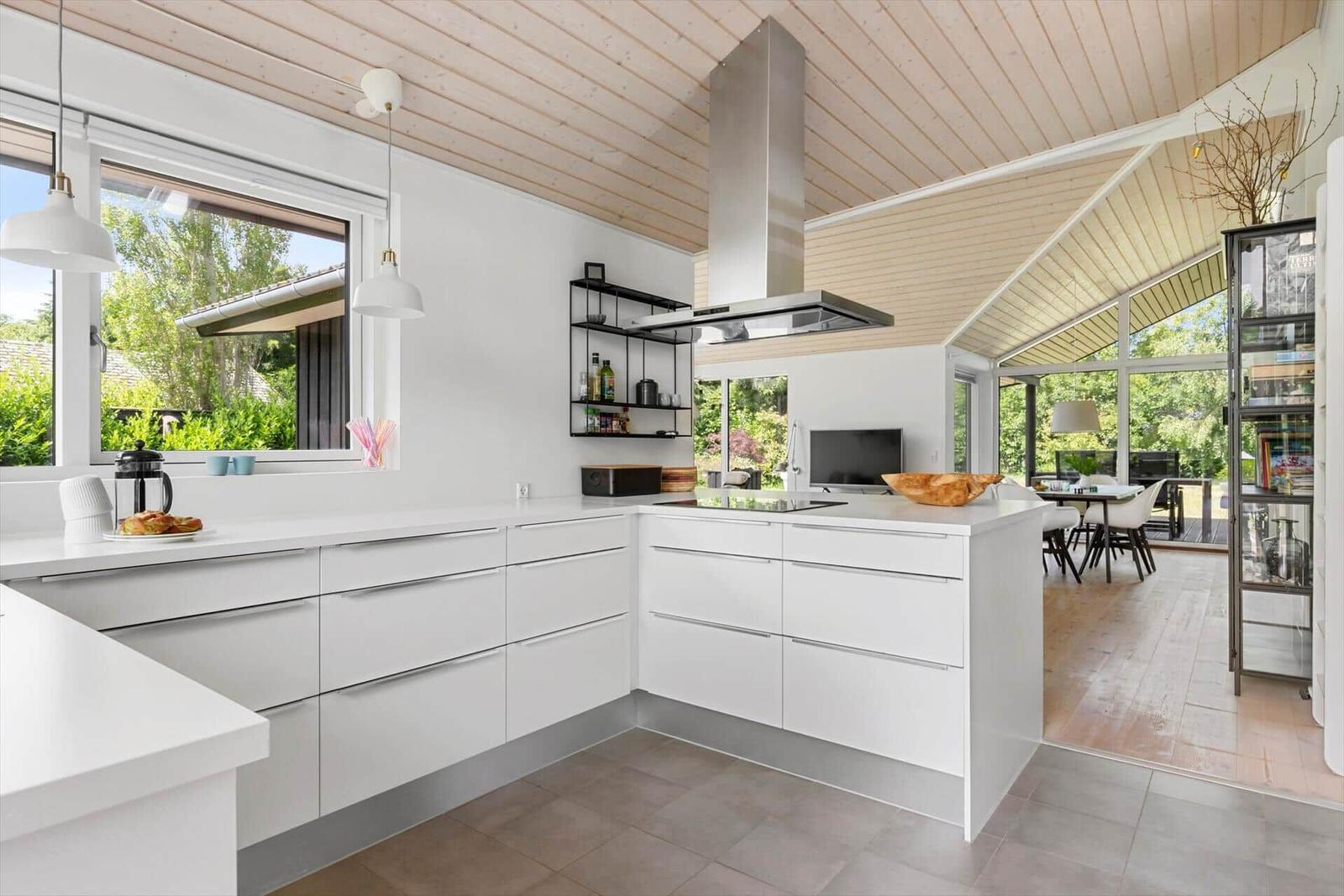 Moderne Küche mit weißen Schränken und Blick auf Garten